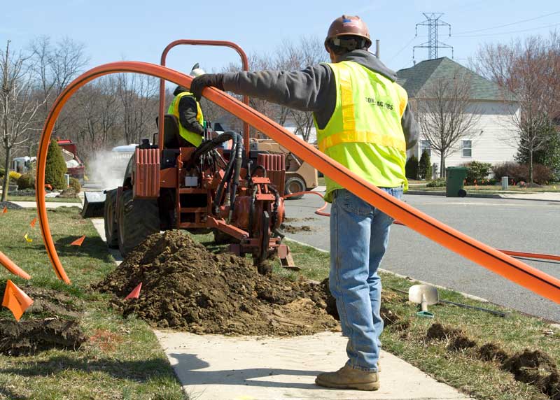 IBEW linemen installing underground conduit in a residential neighborhood using a trenching machine | IBEW Local 71
