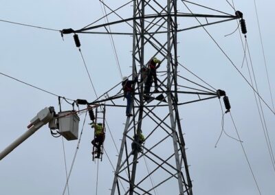 IBEW Local 71 apprentices training on a steel lattice transmission tower with aerial bucket truck support